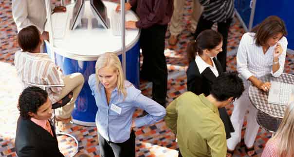 Woman standing with people on the floor of a Detroit trade show exhibit