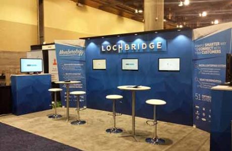 Blue and white example exhibit booth with two tables with stools set up for meetings or demos