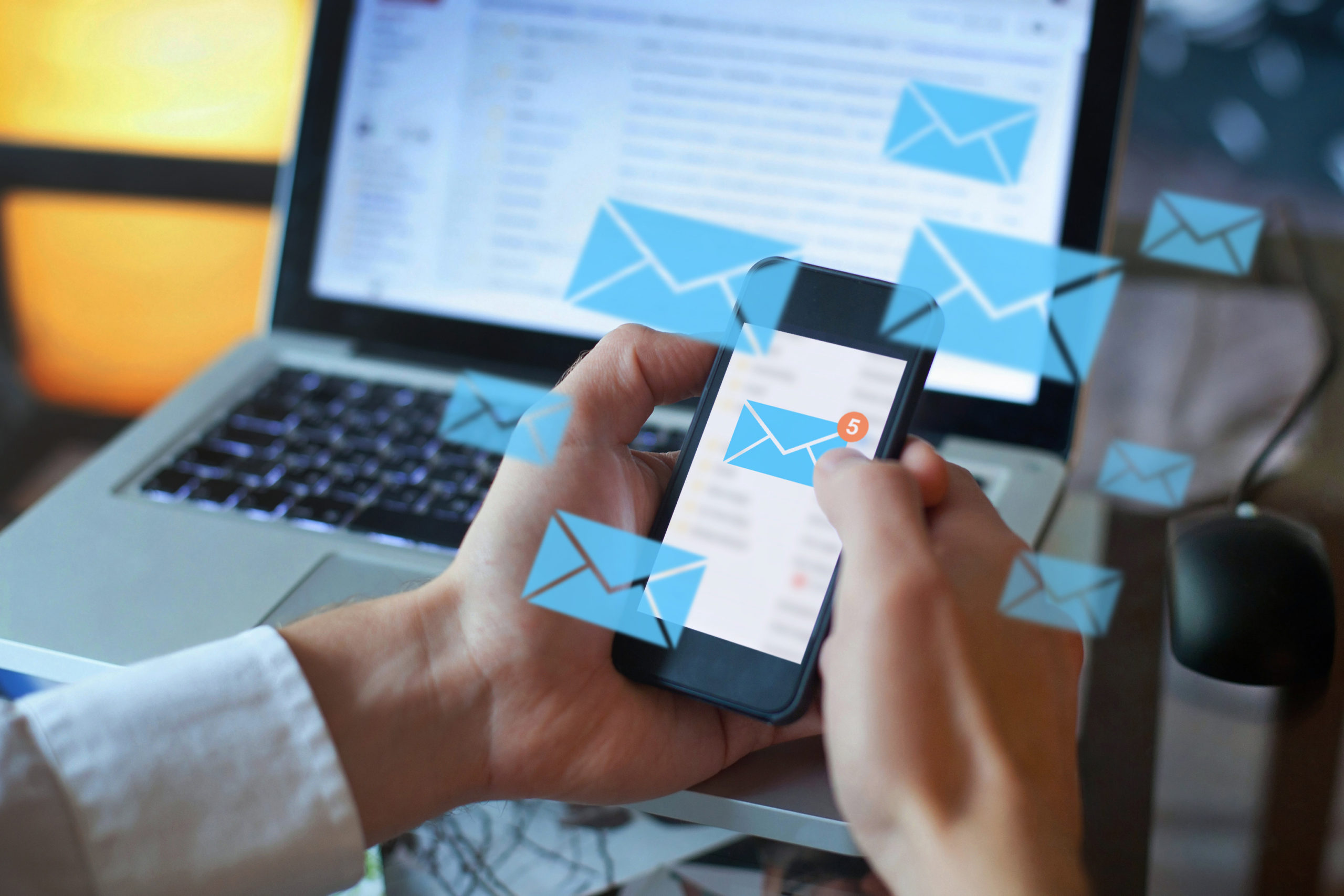 a man holds a cell phone in his hand. The cell phone screen shows a large blue mail notification sign with the number 5, indicating that there are 5 unread emails. Beside the phone are several animated blue mail notification signs.