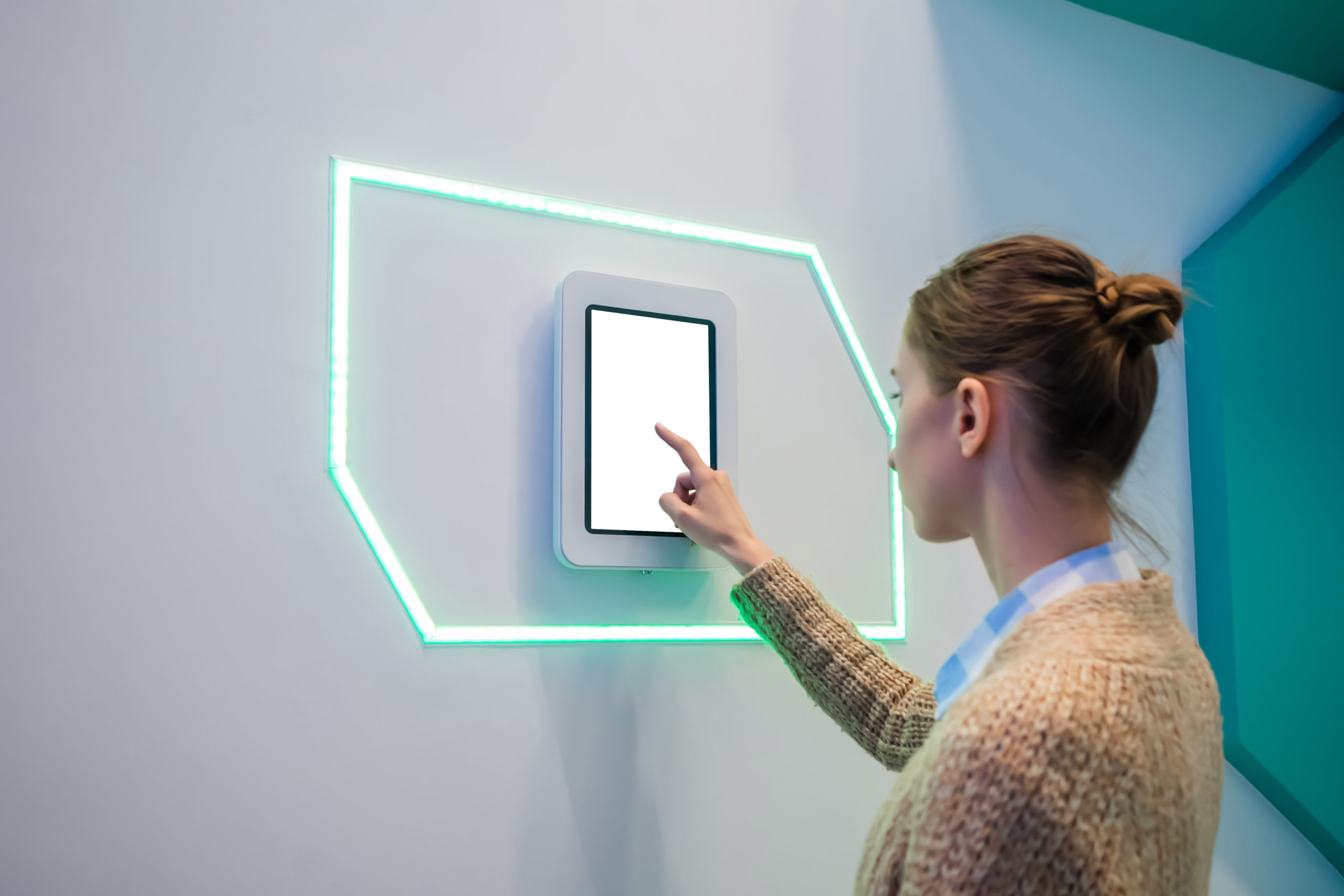 Woman using interactive empty white touchscreen display kiosk at exhibition